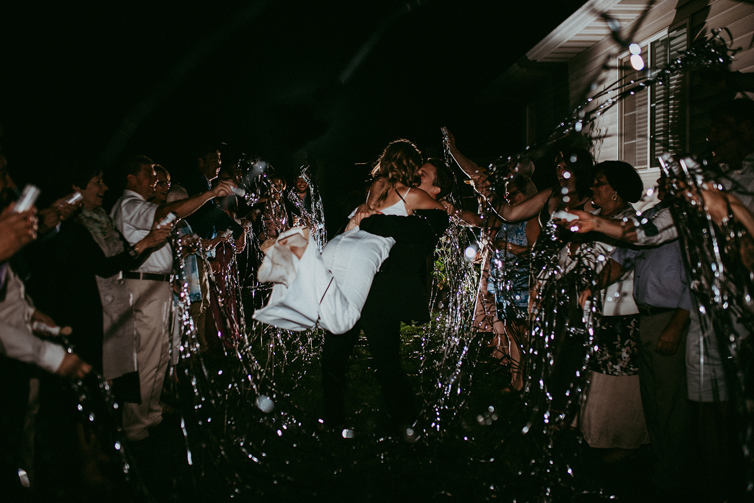 Couple running through a nighttime sparkler send-off as guests cheer on both sides